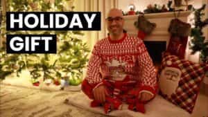 progressive Robot smiling person in red holiday pajamas sits by a lit Christmas tree and fireplace, with text Holiday Gift