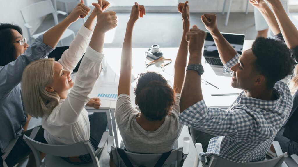 Group of people raising hands in an inclusive workplace workshop