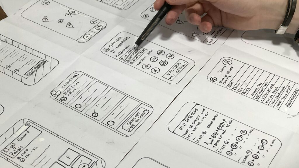 Hand holding a pen over paper prototypes for cognitive accessibility testing