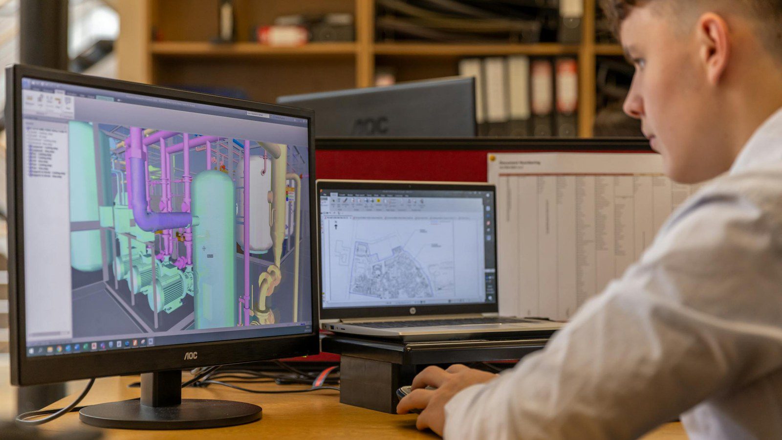 Seed3D 2.0 CAD workflow with an engineer reviewing digital design work on office monitors