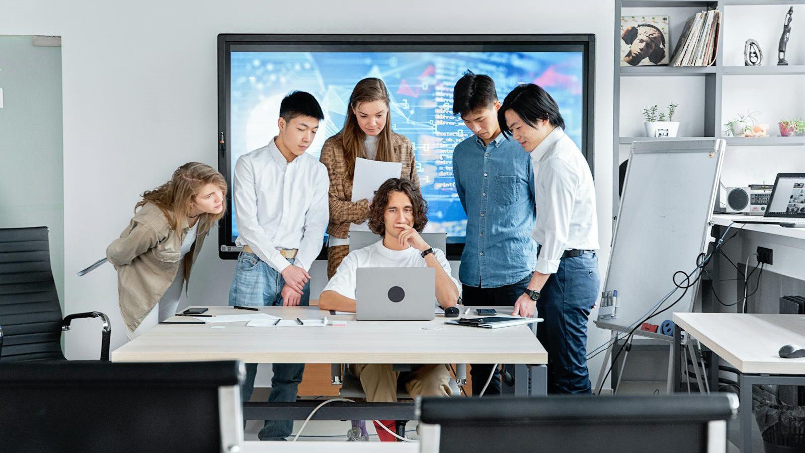 Atoms Review: 7 Smart Ways to Build AI Apps Faster 12 diverse software team reviewing a laptop screen representing AI agents turning ideas into products