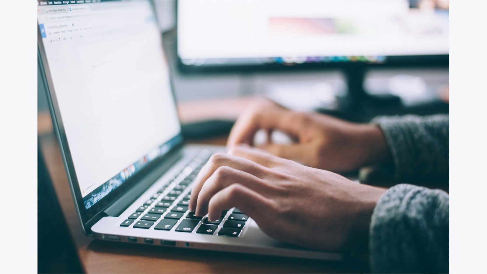 5 Cybersecurity Mistakes That Could Cost Your Small Business Everything 11 Person typing on a MacBook laptop representing cybersecurity mistakes from running unpatched software and outdated systems