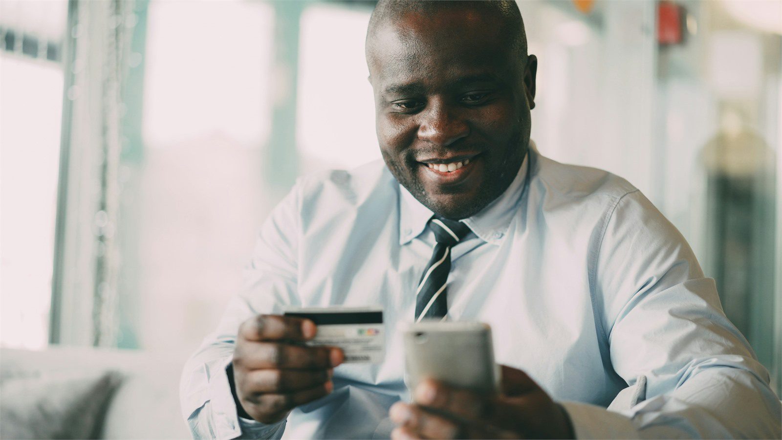 person reviewing a payment card and phone while reading FinTech security protocols FAQ guidance