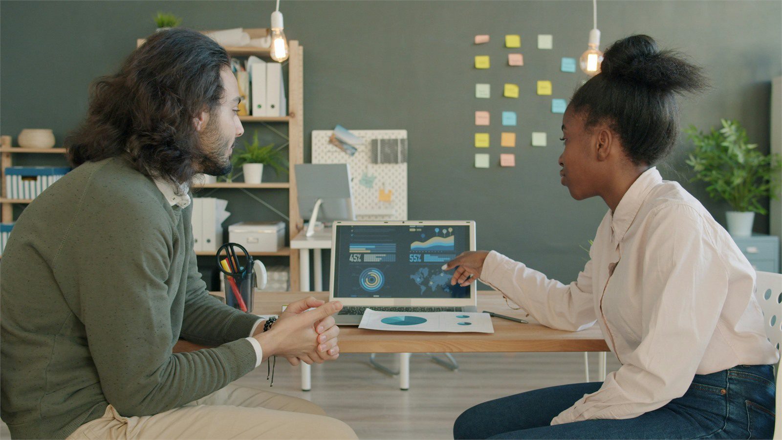colleagues discussing technology budget vendor data and board metrics on laptop
