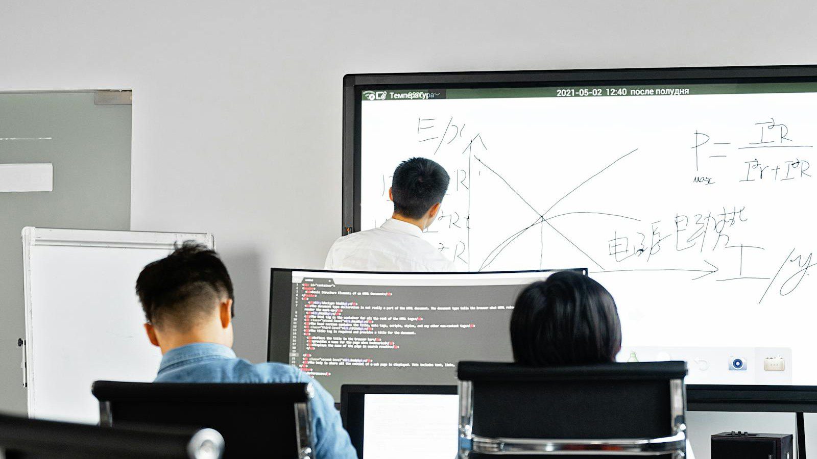 Google Workspace vs Microsoft 365: professionals planning a rollout at a whiteboard with laptops