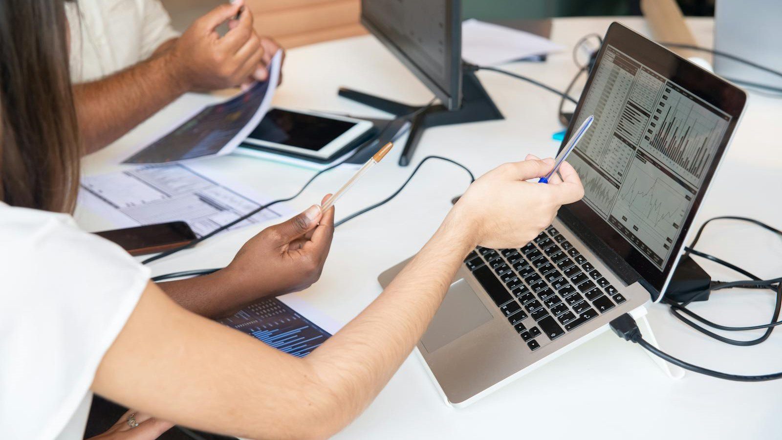 professionals pointing at analytics charts on a laptop for AI Slides presentations