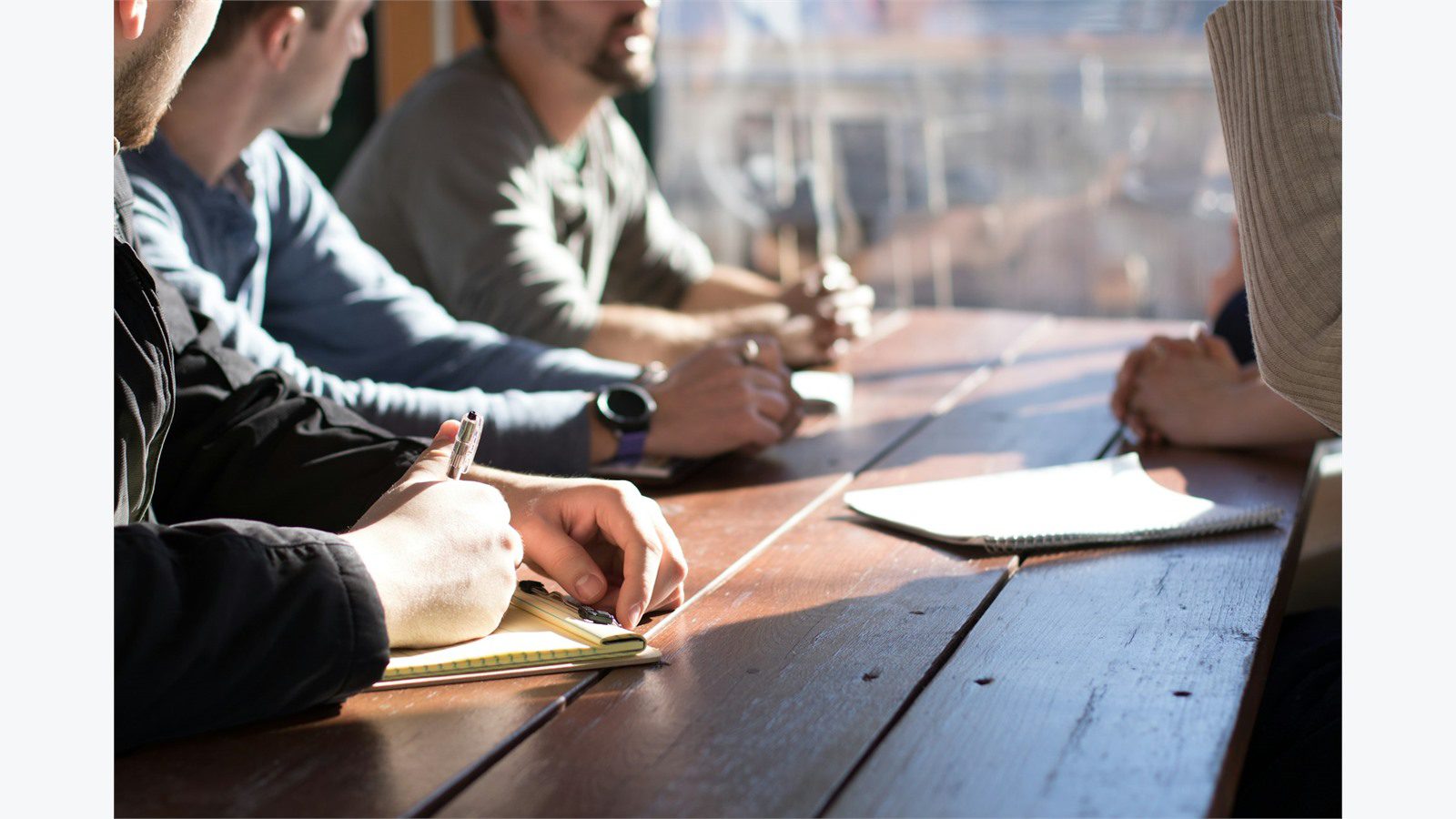 How to Train Your Staff to Detect AI-Powered Phishing Attacks: 8 Proven Steps 21 Team sitting at a table with notes discussing frequently asked questions about AI-powered phishing training