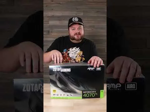 progressive Robot man in a cap sits behind a Zotac Gaming GeForce RTX 4070 Ti graphics card box on a table