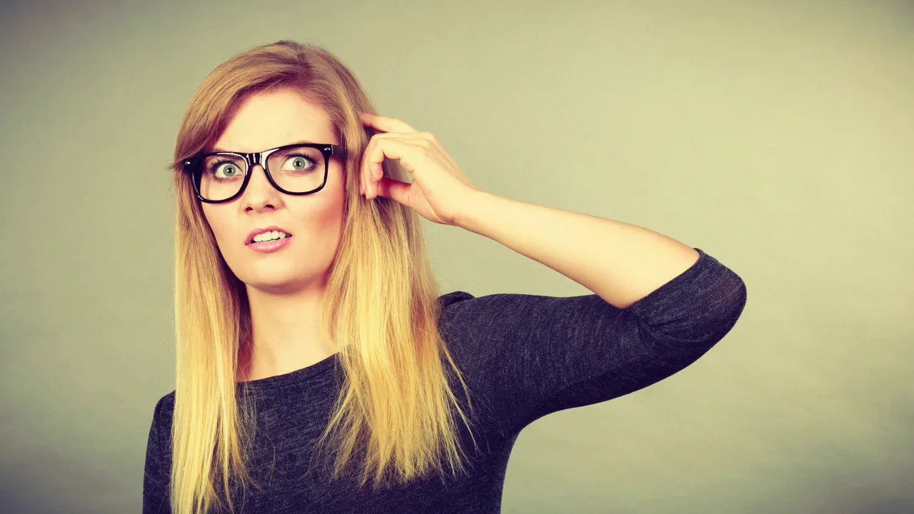progressive Robot confused woman with glasses scratching her head against a plain gray background