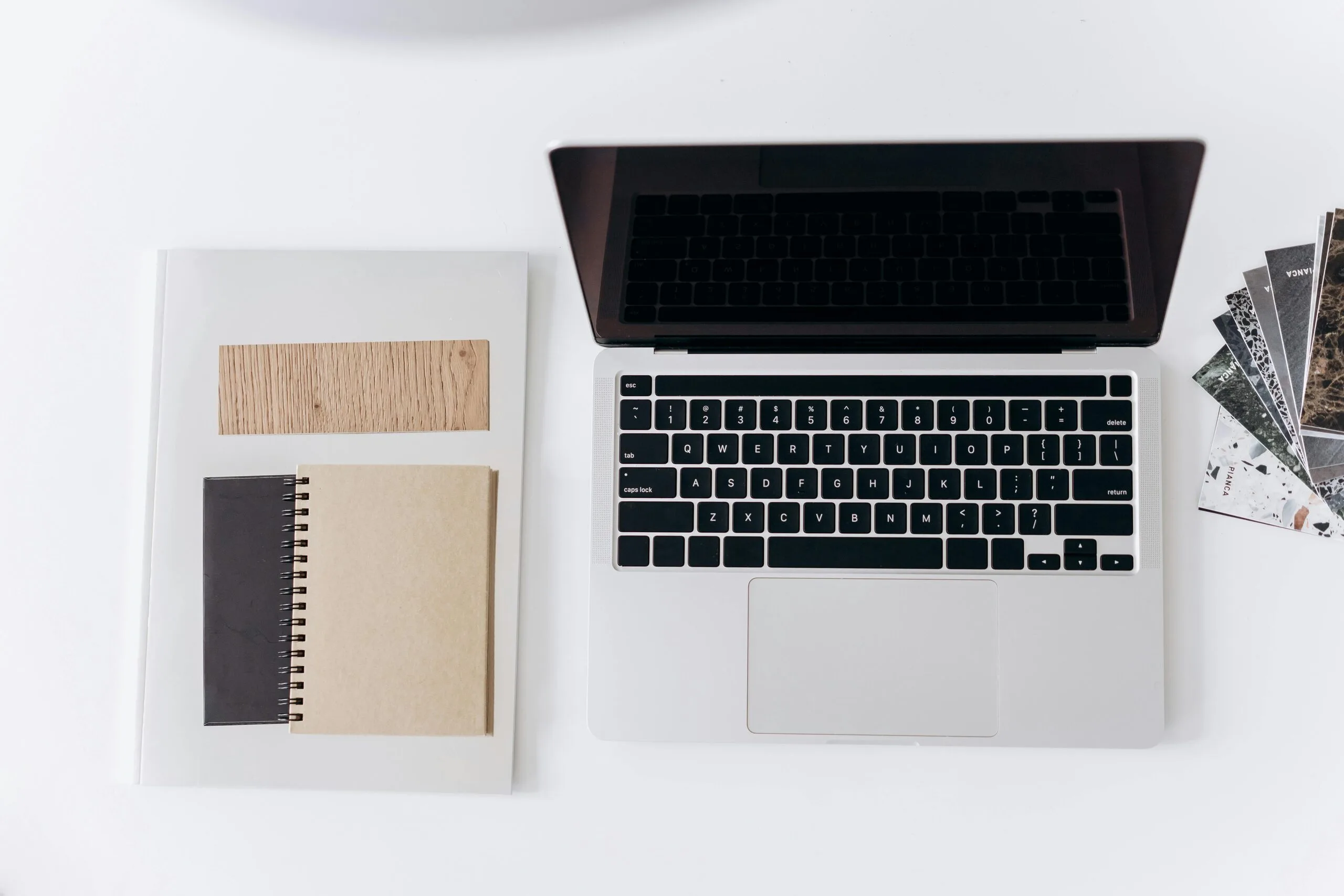 Workspace representing Anthropic launches Claude Design with a laptop, notebook, and design samples
