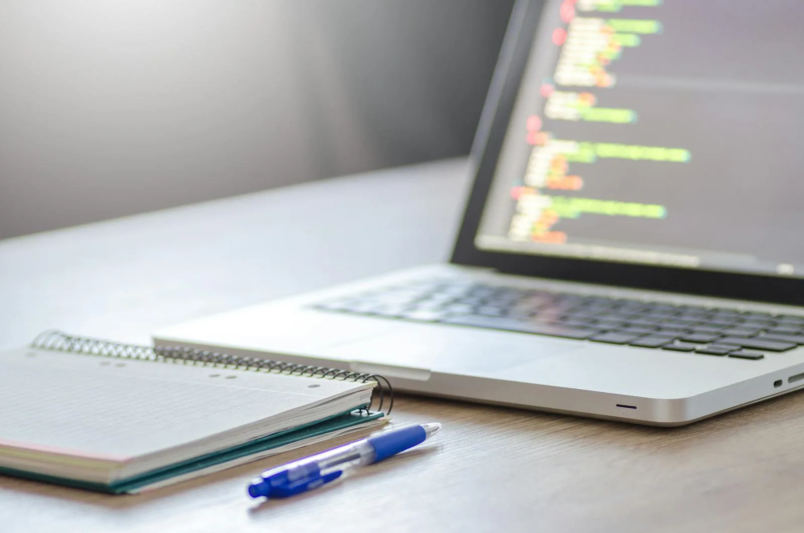 Chattee AI App Builder: 7 Facts About the Prompt-to-App Platform 16 Developer desk with laptop, notebook, and code on screen representing Chattee AI app builder at a glance