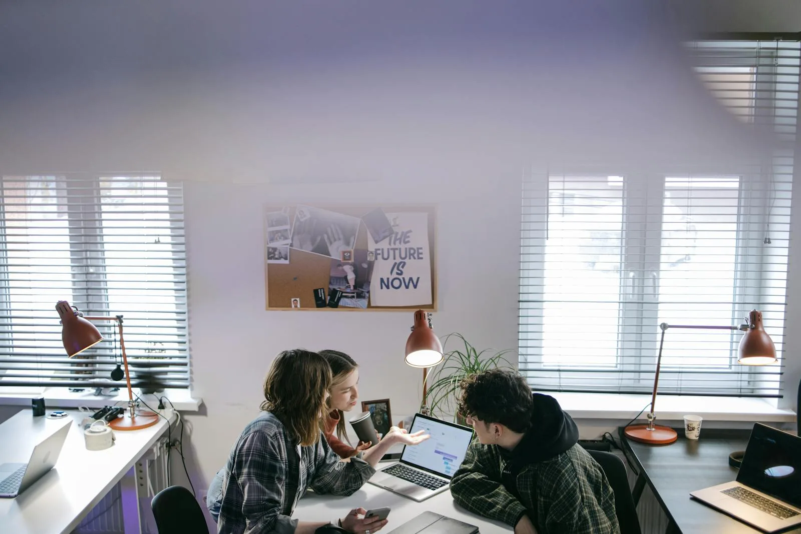 Chattee AI App Builder: 7 Facts About the Prompt-to-App Platform 20 Team gathered around a laptop in a modern office representing the structured facts behind Chattee AI app builder