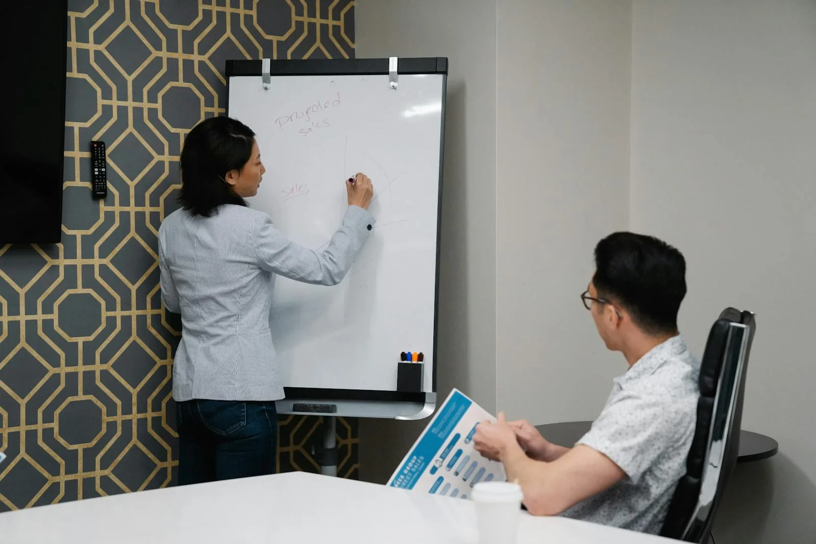 Chattee AI App Builder: 7 Facts About the Prompt-to-App Platform 24 Two coworkers discussing notes on a whiteboard representing common questions about Chattee AI app builder
