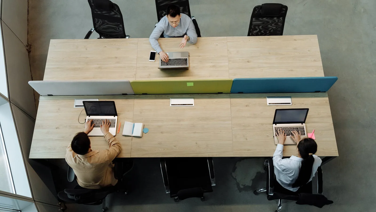 GPT for Work FAQ represented by coworkers discussing work on laptops in an office