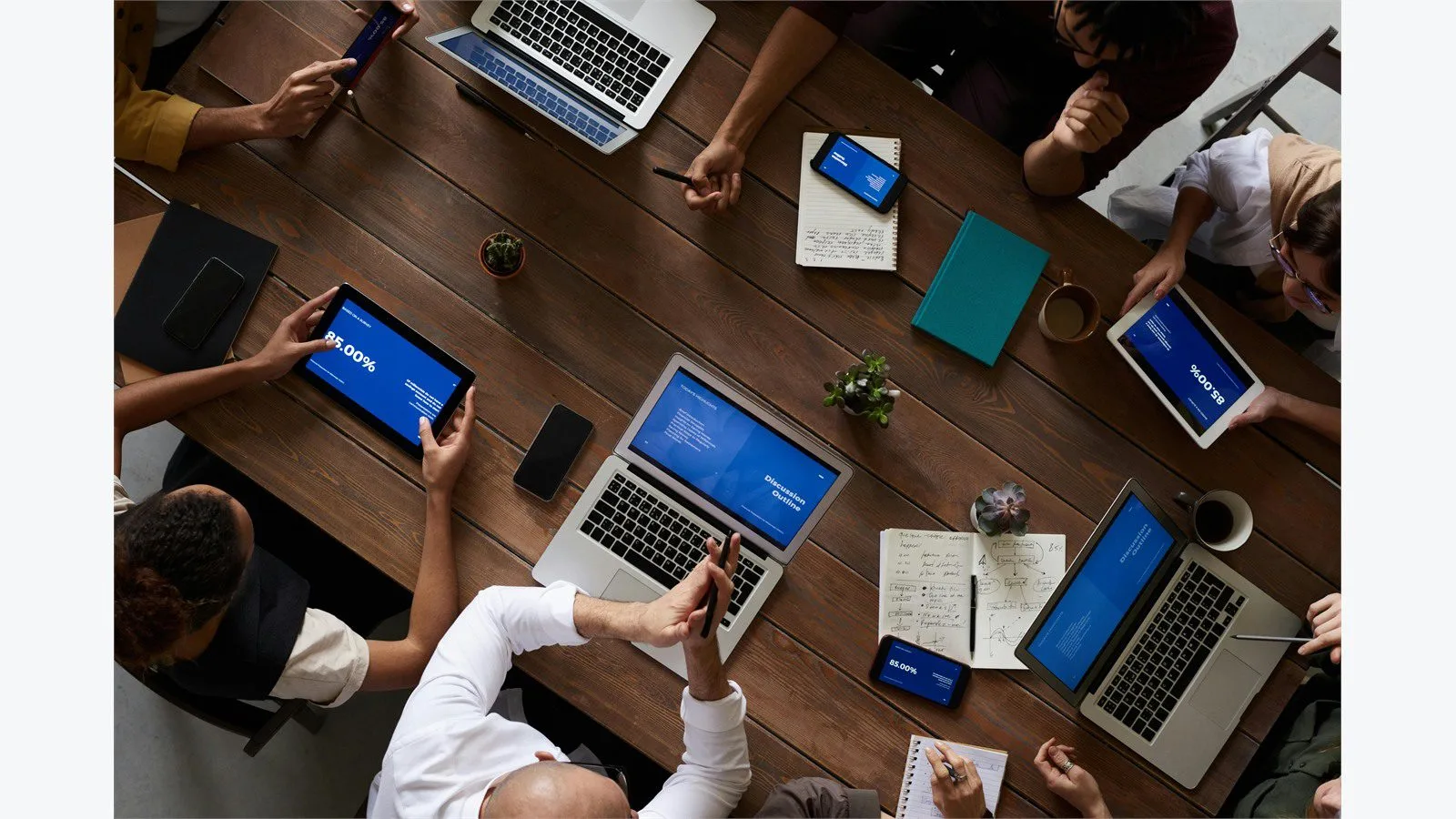 AngularJS End of Life in 2026: 7 Smart Moves for Legacy Apps 16 Overhead view of a team coordinating a phased rollout plan around laptops and notes
