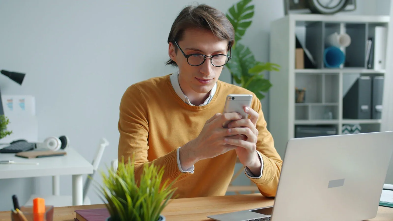 Noscroll AI concept showing a professional checking phone updates at a laptop desk
