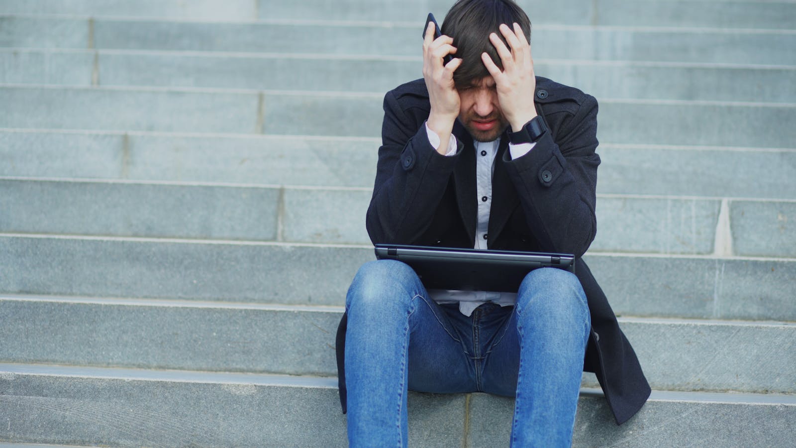 Stressed laptop user representing urgent response to a deepfake brand incident